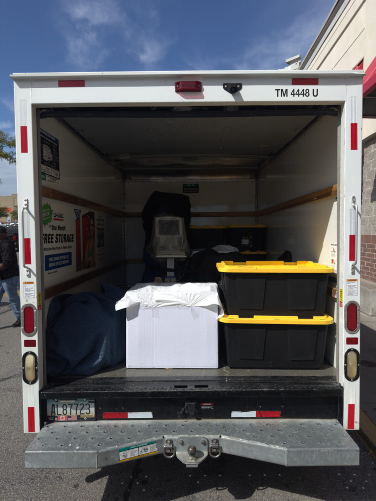 Open moving truck partially loaded with padded furniture and bins