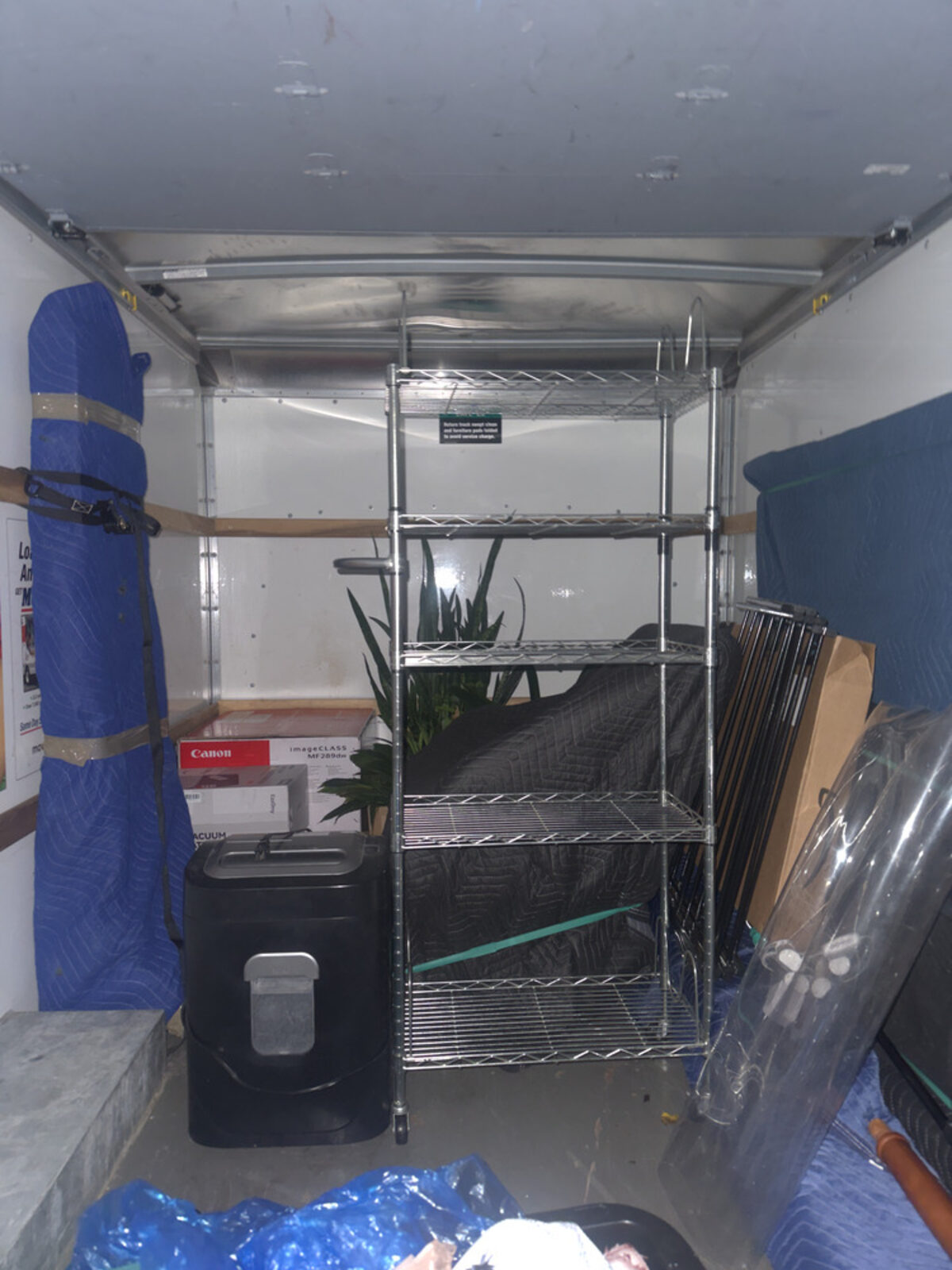 Moving truck interior organized with a shelving unit and padded pieces